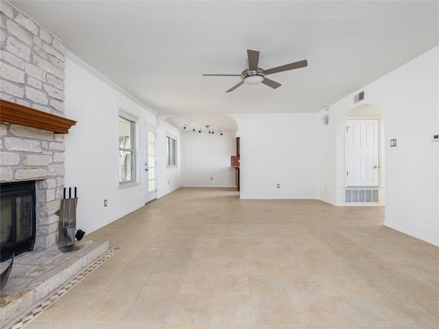 12208 Antoinette Pl, Austin, TX 78727 - unfurnished living room featuring a ceiling fan, a stone fireplace, arched walkways, and baseboards