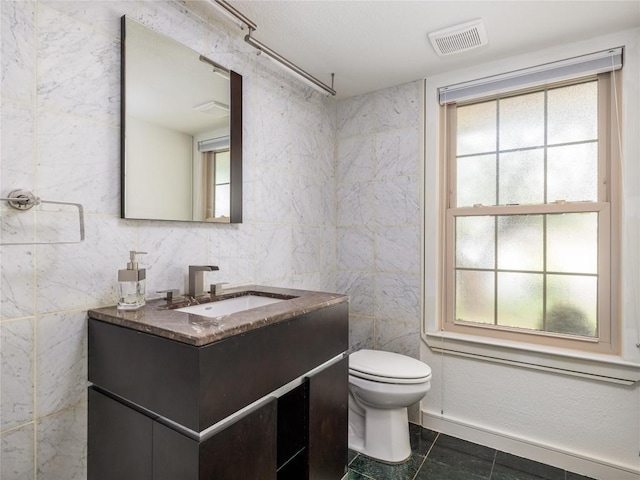 12208 Antoinette Pl, Austin, TX 78727 - bathroom featuring vanity, tile walls, healthy amount of natural light, and toilet