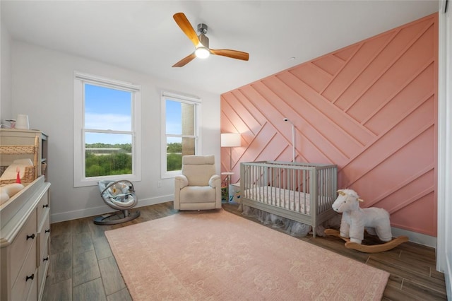 4702 Unity Cir, Austin, TX 78731 - bedroom featuring a crib, dark wood-type flooring, baseboards, and ceiling fan