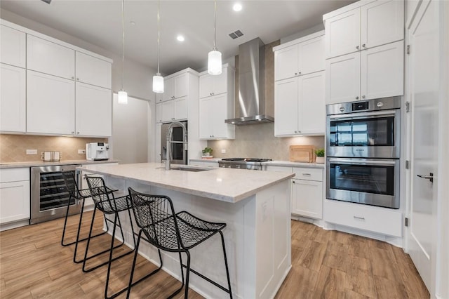 4702 Unity Cir, Austin, TX 78731 - kitchen with wine cooler, appliances with stainless steel finishes, wall chimney range hood, a sink, and recessed lighting
