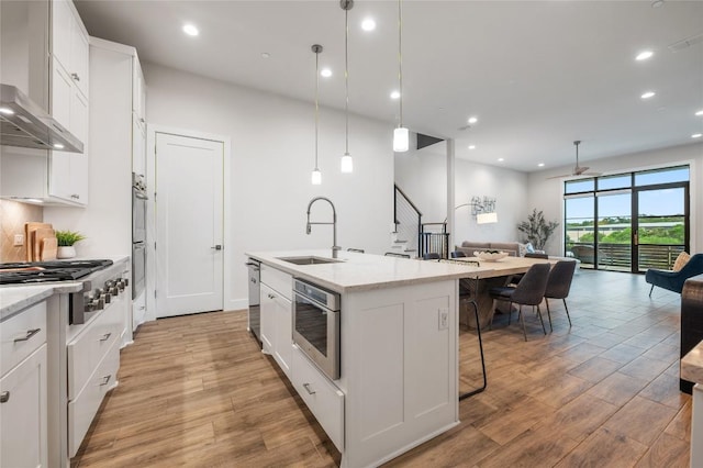 4702 Unity Cir, Austin, TX 78731 - kitchen with a sink, appliances with stainless steel finishes, open floor plan, wall chimney range hood, and light wood-type flooring