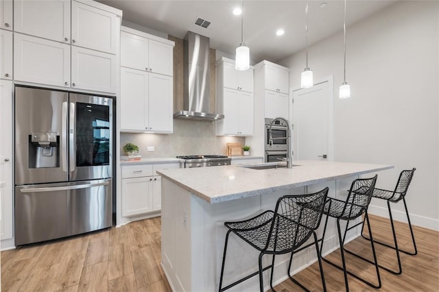 4702 Unity Cir, Austin, TX 78731 - kitchen featuring appliances with stainless steel finishes, wall chimney exhaust hood, a sink, light wood-style flooring, and white cabinets