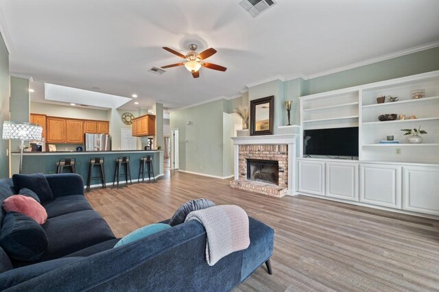 8007 Weldon Springs Ct, Austin, TX 78726 - living area with crown molding, a ceiling fan, light wood-style floors, and a fireplace