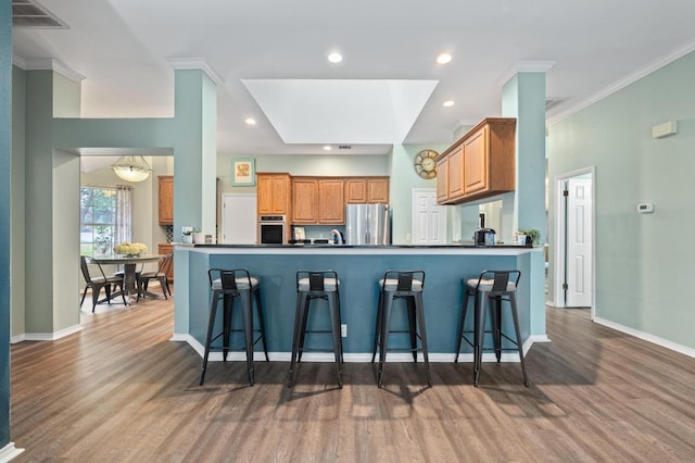 8007 Weldon Springs Ct, Austin, TX 78726 - kitchen with stainless steel appliances, a breakfast bar, wood finished floors, dark countertops, and ornamental molding