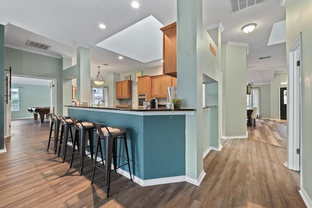 8007 Weldon Springs Ct, Austin, TX 78726 - kitchen with a kitchen bar, wood finished floors, dark countertops, recessed lighting, and crown molding