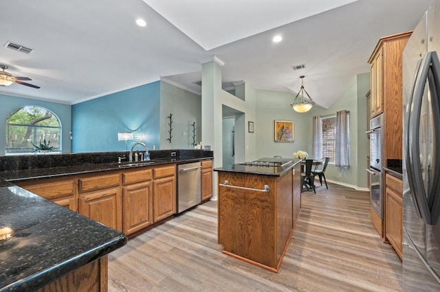 8007 Weldon Springs Ct, Austin, TX 78726 - kitchen featuring appliances with stainless steel finishes, light wood finished floors, brown cabinetry, a kitchen island, and dark stone countertops