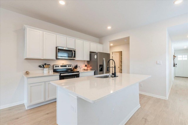 185 Standing Rock Ln, Marble Falls, TX 78654 - kitchen featuring appliances with stainless steel finishes, a sink, light wood-type flooring, an island with sink, and white cabinetry