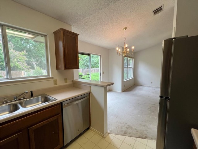 6612 Zequiel Dr, Austin, TX 78744 - kitchen with appliances with stainless steel finishes, light carpet, a sink, a textured ceiling, and a chandelier