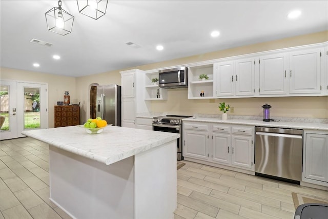 1313 Oakridge Dr, Blanco, TX 78606 - kitchen with appliances with stainless steel finishes, open shelves, a kitchen island, white cabinetry, and arched walkways