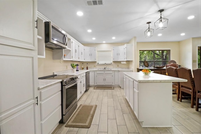 1313 Oakridge Dr, Blanco, TX 78606 - kitchen featuring stainless steel appliances, light countertops, a kitchen island, wood finish floors, and white cabinetry
