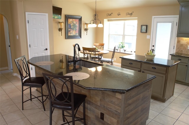 2721 Saddle Blanket Pl, Leander, TX 78641 - kitchen featuring a center island with sink, light tile patterned floors, a breakfast bar, dark stone counters, and a chandelier