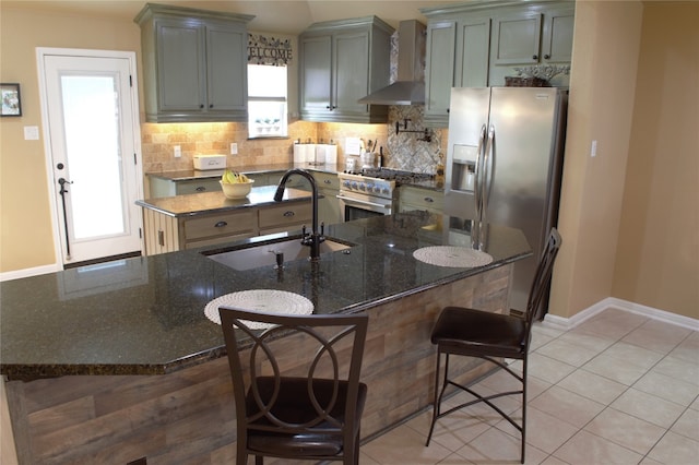 2721 Saddle Blanket Pl, Leander, TX 78641 - kitchen featuring wall chimney range hood, stainless steel appliances, an island with sink, tasteful backsplash, and dark stone counters