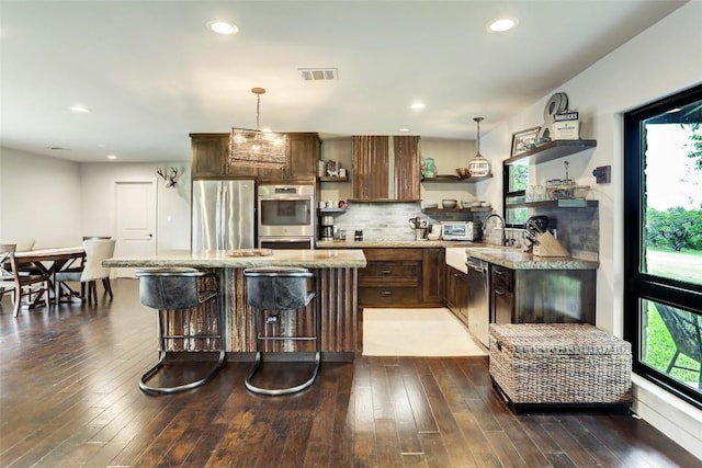 11700 Rim Rock Trl, Austin, TX 78737 - kitchen with open shelves, stainless steel appliances, a kitchen island, a kitchen breakfast bar, and pendant lighting
