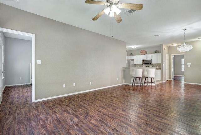 1003 E 3rd St, Georgetown, TX 78626 - living room with a ceiling fan, dark wood finished floors, baseboards, and a chandelier