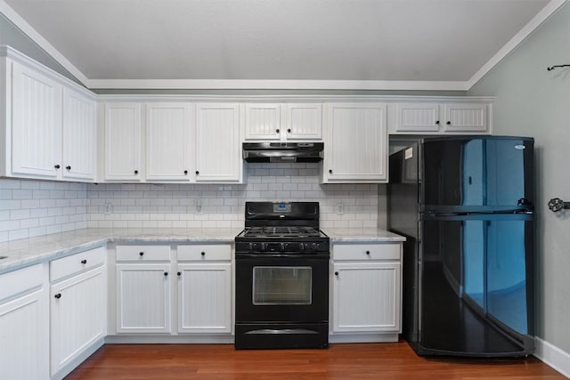 1011 Moser River Dr, Leander, TX 78641 - kitchen featuring black appliances, under cabinet range hood, ornamental molding, dark wood-style floors, and tasteful backsplash