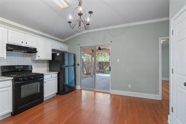 1011 Moser River Dr, Leander, TX 78641 - kitchen with black appliances, under cabinet range hood, crown molding, a chandelier, and white cabinets
