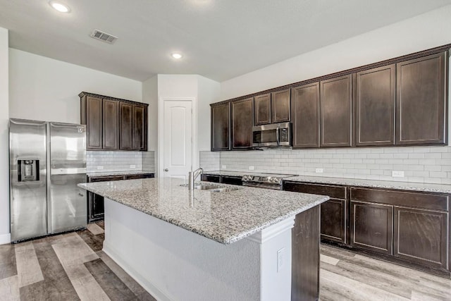 1905 Mariann Dr, Leander, TX 78641 - kitchen featuring stainless steel appliances, light stone counters, dark brown cabinetry, light wood-style floors, and recessed lighting
