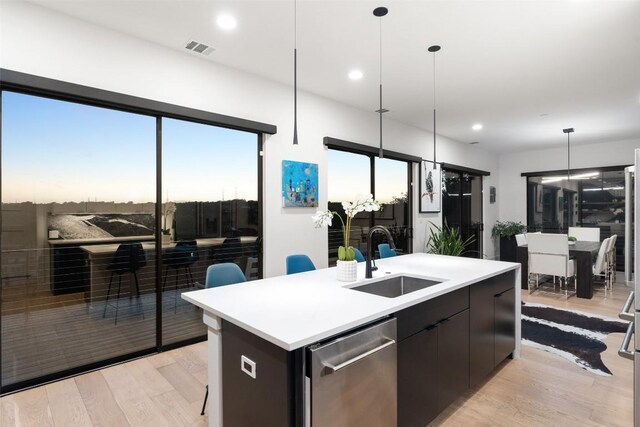 14417 Cochise Trl, Austin, TX 78734 - kitchen with a sink, an island with sink, light wood-type flooring, light countertops, and stainless steel dishwasher