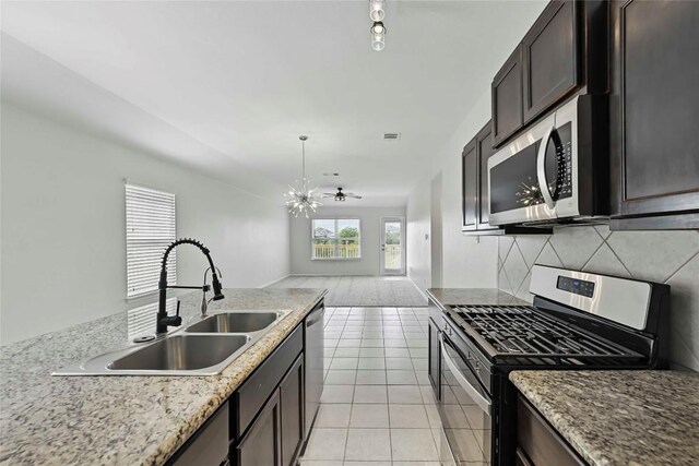 146 Blair Ct, San Marcos, TX 78666 - kitchen with appliances with stainless steel finishes, a chandelier, backsplash, light tile patterned floors, and open floor plan