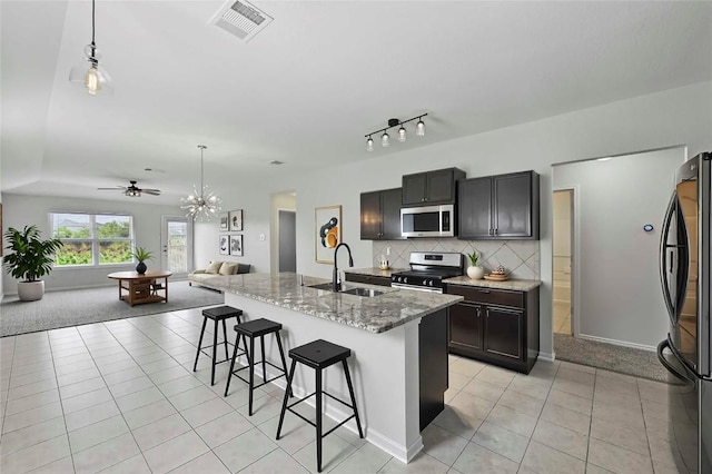 146 Blair Ct, San Marcos, TX 78666 - kitchen with stainless steel appliances, open floor plan, a breakfast bar, light tile patterned flooring, and light stone countertops