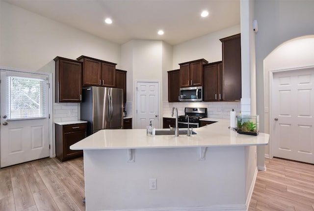 216 Walkup Ln, Leander, TX 78641 - kitchen featuring stainless steel appliances, dark brown cabinets, a peninsula, light wood finished floors, and recessed lighting
