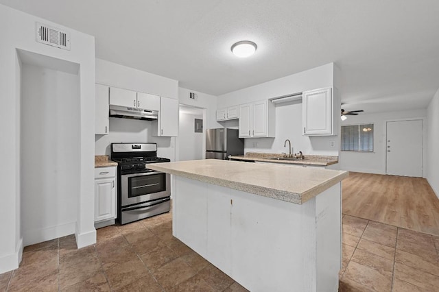 2303 E E Side Dr Unit 102, Austin, TX 78704 - kitchen with appliances with stainless steel finishes, under cabinet range hood, light countertops, and white cabinetry