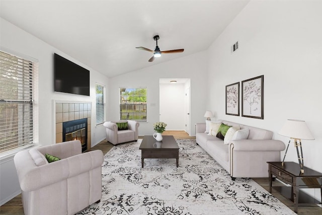 2205 Thornwild Pass, Austin, TX 78758 - living area with a tiled fireplace, ceiling fan, vaulted ceiling, and wood finished floors