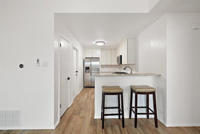 2205 Thornwild Pass, Austin, TX 78758 - kitchen featuring stainless steel appliances, a breakfast bar, a peninsula, and light wood-style flooring