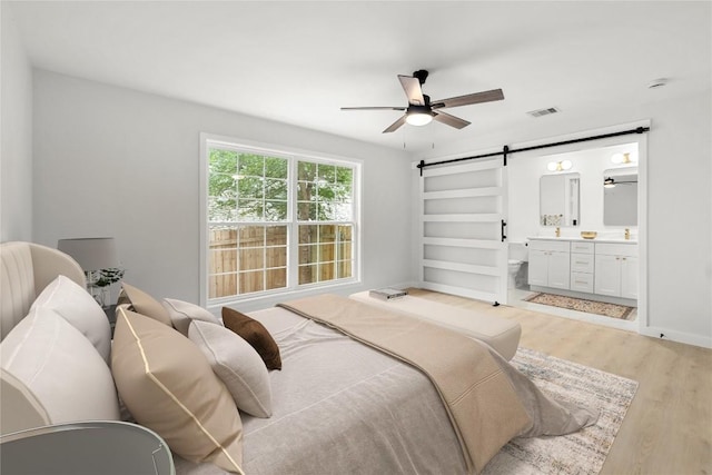 913 Spring Tree St, Round Rock, TX 78681 - bedroom featuring a barn door, light wood-style floors, and connected bathroom