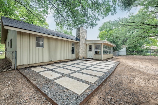 1906 Garden Villa Dr, Georgetown, TX 78628 - back of property with a chimney, a sunroom, a patio, board and batten siding, and roof with shingles