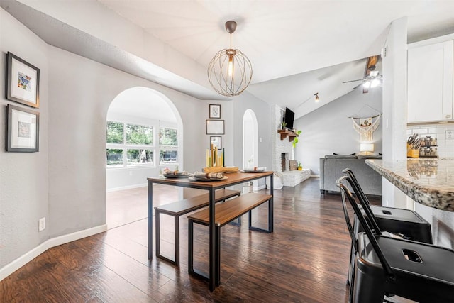 1906 Garden Villa Dr, Georgetown, TX 78628 - dining space featuring arched walkways, a ceiling fan, vaulted ceiling, dark wood-type flooring, and a large fireplace