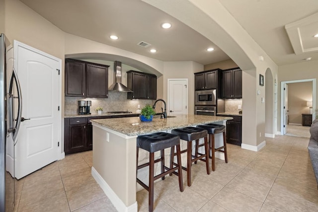 2644 Salorn Way, Round Rock, TX 78681 - kitchen with wall chimney range hood, stainless steel appliances, tasteful backsplash, light tile patterned flooring, and a kitchen breakfast bar