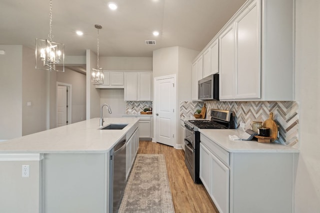 1116 Highwater Dr, Georgetown, TX 78628 - kitchen with a sink, appliances with stainless steel finishes, light wood-style flooring, white cabinetry, and a center island with sink