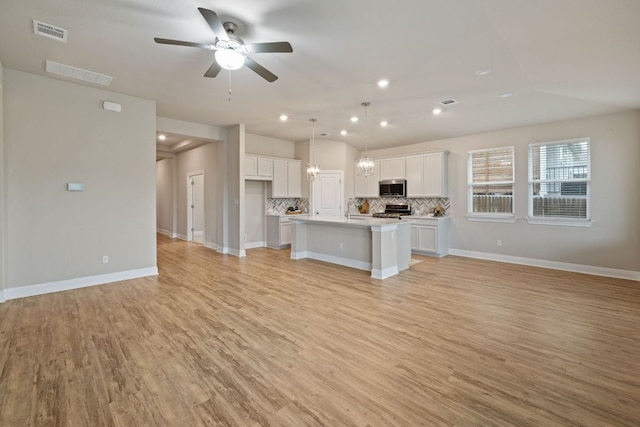 1116 Highwater Dr, Georgetown, TX 78628 - kitchen with appliances with stainless steel finishes, open floor plan, decorative backsplash, white cabinets, and a ceiling fan