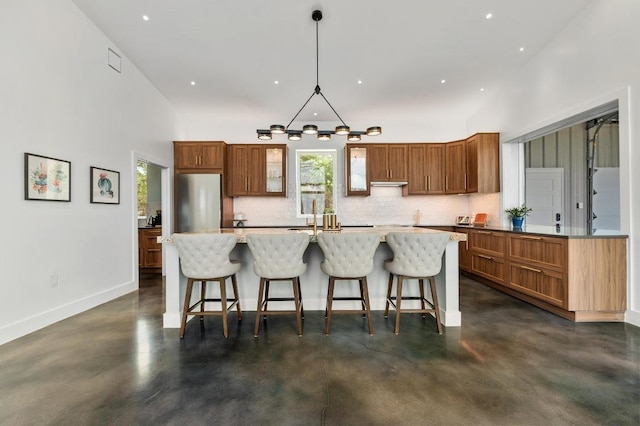 2300 Stagecoach Ranch Loop Unit B, Dripping Springs, TX 78620 - kitchen featuring finished concrete floors, decorative backsplash, a center island, brown cabinetry, and a kitchen bar