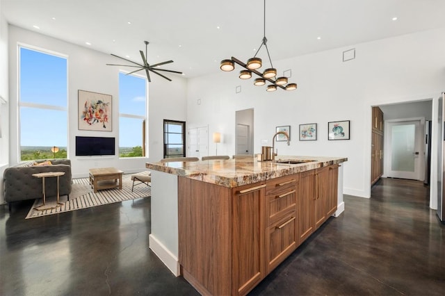 2300 Stagecoach Ranch Loop Unit B, Dripping Springs, TX 78620 - kitchen with a sink, a towering ceiling, finished concrete floors, brown cabinets, and light stone countertops
