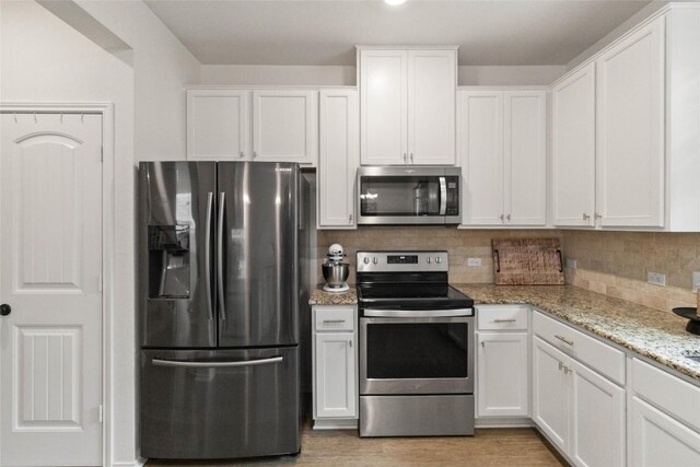 9003 Acorn Cup Dr Unit 34, Austin, TX 78748 - kitchen with stainless steel appliances, white cabinetry, decorative backsplash, light stone countertops, and light wood-style floors