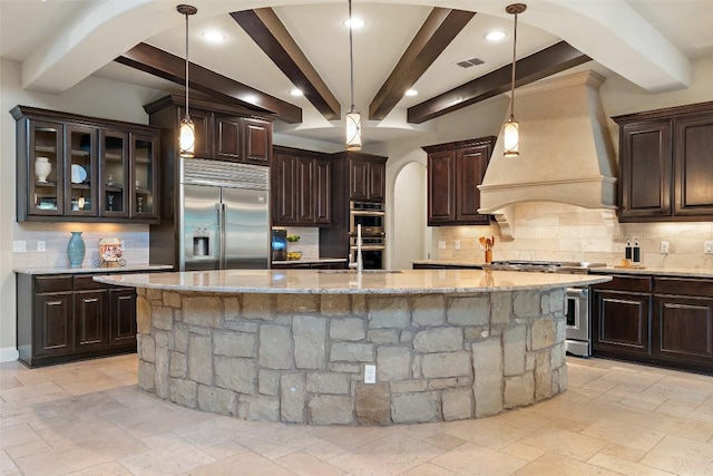303 Bella Montagna Cir, Austin, TX 78734 - kitchen featuring stainless steel appliances, custom exhaust hood, beamed ceiling, backsplash, and stone tile flooring