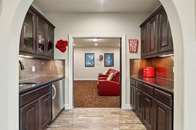 303 Bella Montagna Cir, Austin, TX 78734 - kitchen with dark brown cabinetry, dark stone counters, glass insert cabinets, and light wood-style flooring