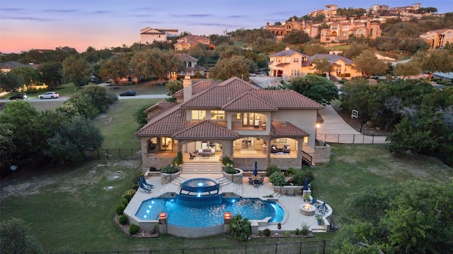303 Bella Montagna Cir, Austin, TX 78734 - back of property at dusk with a tile roof, a balcony, a fenced backyard, stucco siding, and a chimney