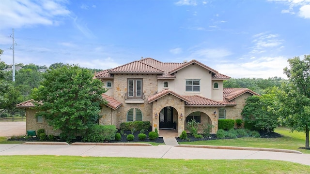 303 Bella Montagna Cir, Austin, TX 78734 - mediterranean / spanish-style house featuring stone siding, a tiled roof, a front lawn, and stucco siding