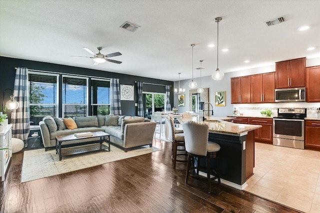 257 Culebra Dr, Georgetown, TX 78626 - kitchen with appliances with stainless steel finishes, open floor plan, a breakfast bar, light stone counters, and a ceiling fan