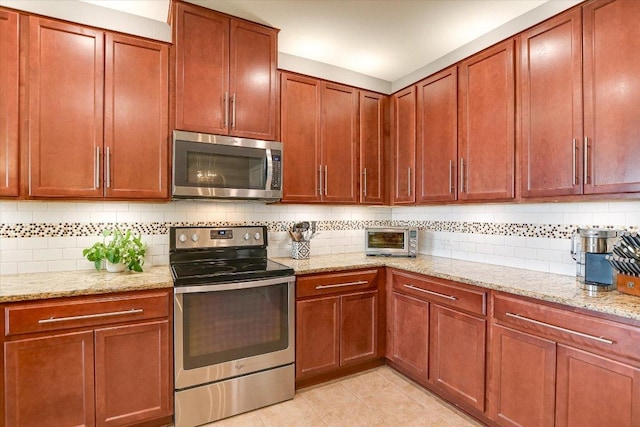 257 Culebra Dr, Georgetown, TX 78626 - kitchen featuring appliances with stainless steel finishes, tasteful backsplash, light stone countertops, light tile patterned floors, and brown cabinets