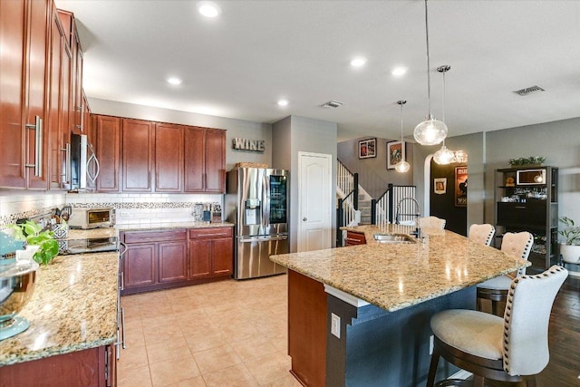 257 Culebra Dr, Georgetown, TX 78626 - kitchen with stainless steel appliances, a sink, tasteful backsplash, a kitchen breakfast bar, and light stone countertops