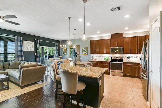 257 Culebra Dr, Georgetown, TX 78626 - kitchen featuring stainless steel appliances, a sink, a ceiling fan, light stone countertops, and backsplash
