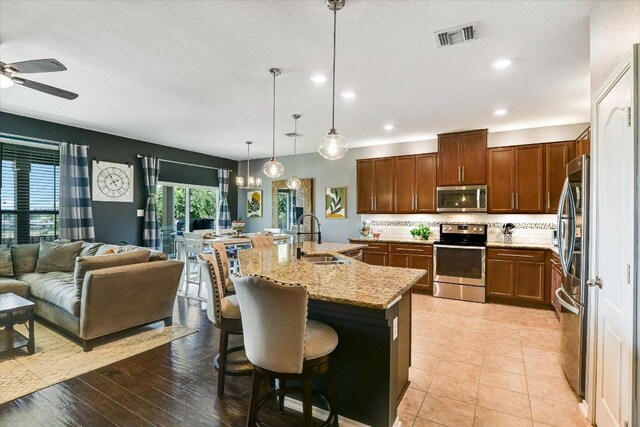 257 Culebra Dr, Georgetown, TX 78626 - kitchen with stainless steel appliances, ceiling fan, light stone countertops, tasteful backsplash, and open floor plan