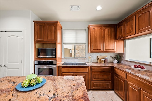 8546 Adirondack Trl Unit 14, Austin, TX 78759 - kitchen with appliances with stainless steel finishes, light stone countertops, light tile patterned flooring, tasteful backsplash, and brown cabinetry
