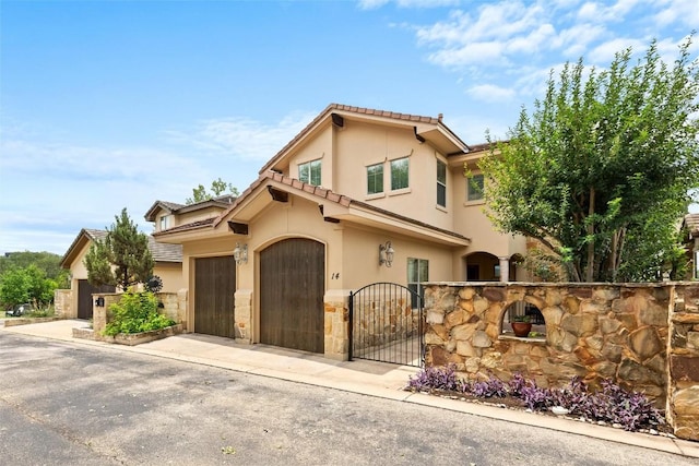 8546 Adirondack Trl Unit 14, Austin, TX 78759 - view of front of home featuring stucco siding, a gate, a tiled roof, a garage, and driveway