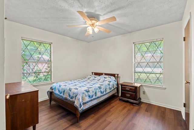 814 W Bell Ave, Rockdale, TX 76567 - bedroom featuring multiple windows, dark wood-style floors, baseboards, a textured ceiling, and a ceiling fan
