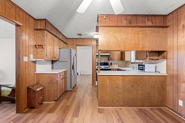 814 W Bell Ave, Rockdale, TX 76567 - kitchen with stainless steel refrigerator with ice dispenser, stove, a textured ceiling, white microwave, and light wood finished floors